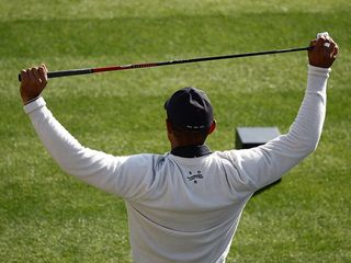 Tiger Woods stretching using a golf club