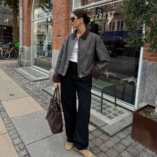 Fashion influencer @maryljean in Copenhagen wearing an on-trend outfit for spring 2025 with a contrast collar jacket, Miu Miu bag and sunglasses, relaxed trousers, white tee, and suede boat shoes.