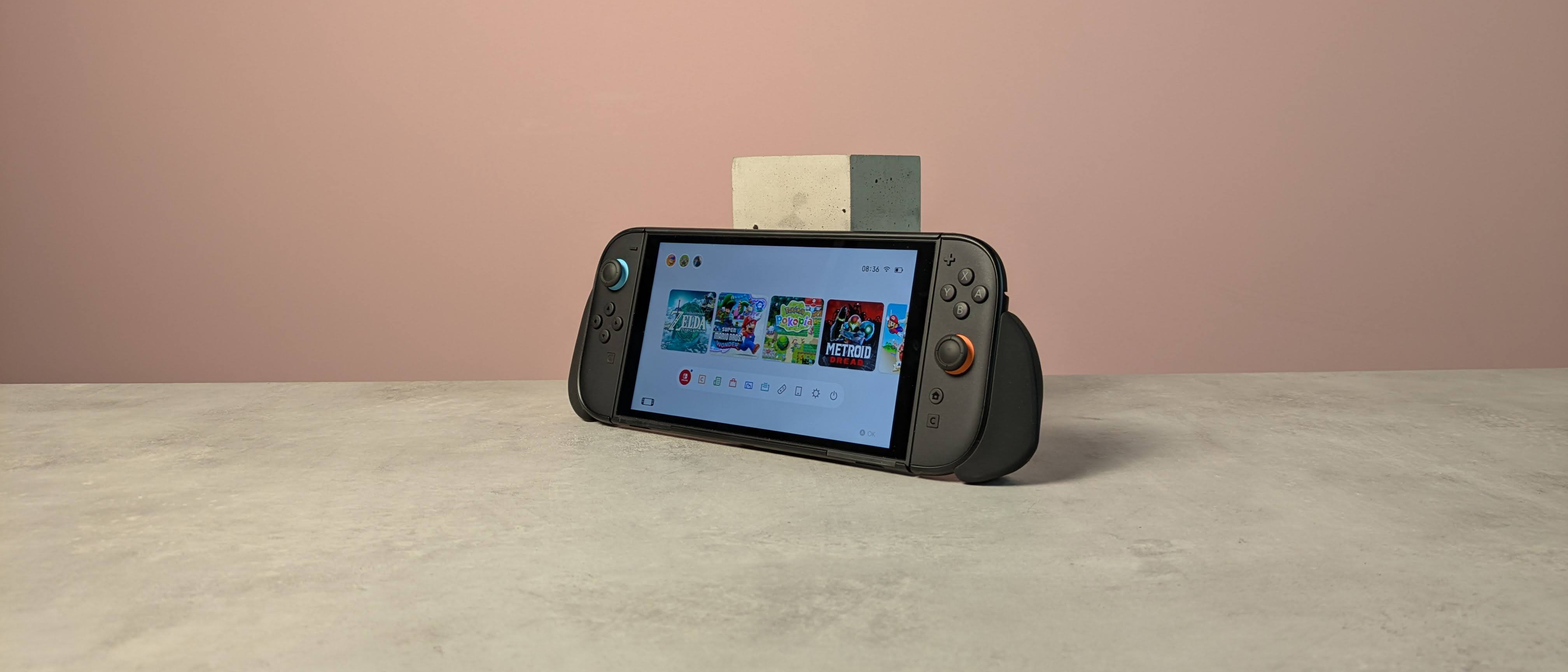 Nintendo Switch 2 leaning against plinth on desk with Genki Attack Vector attached, against a pink background