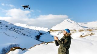 man flying drone in snowy mountains