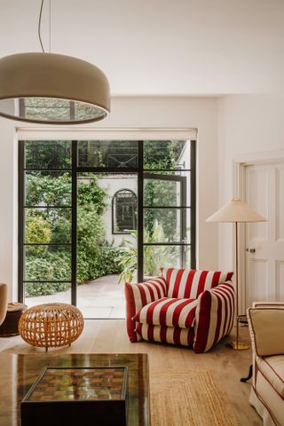 Living room with beige walls, beige chair and sofa, and red and white striped armchair