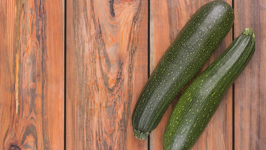 two zucchinis on a wooden surface