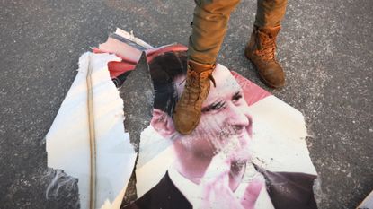 Rebel fighter steps on torn photo of Syria's deposed Bashar al-Assad