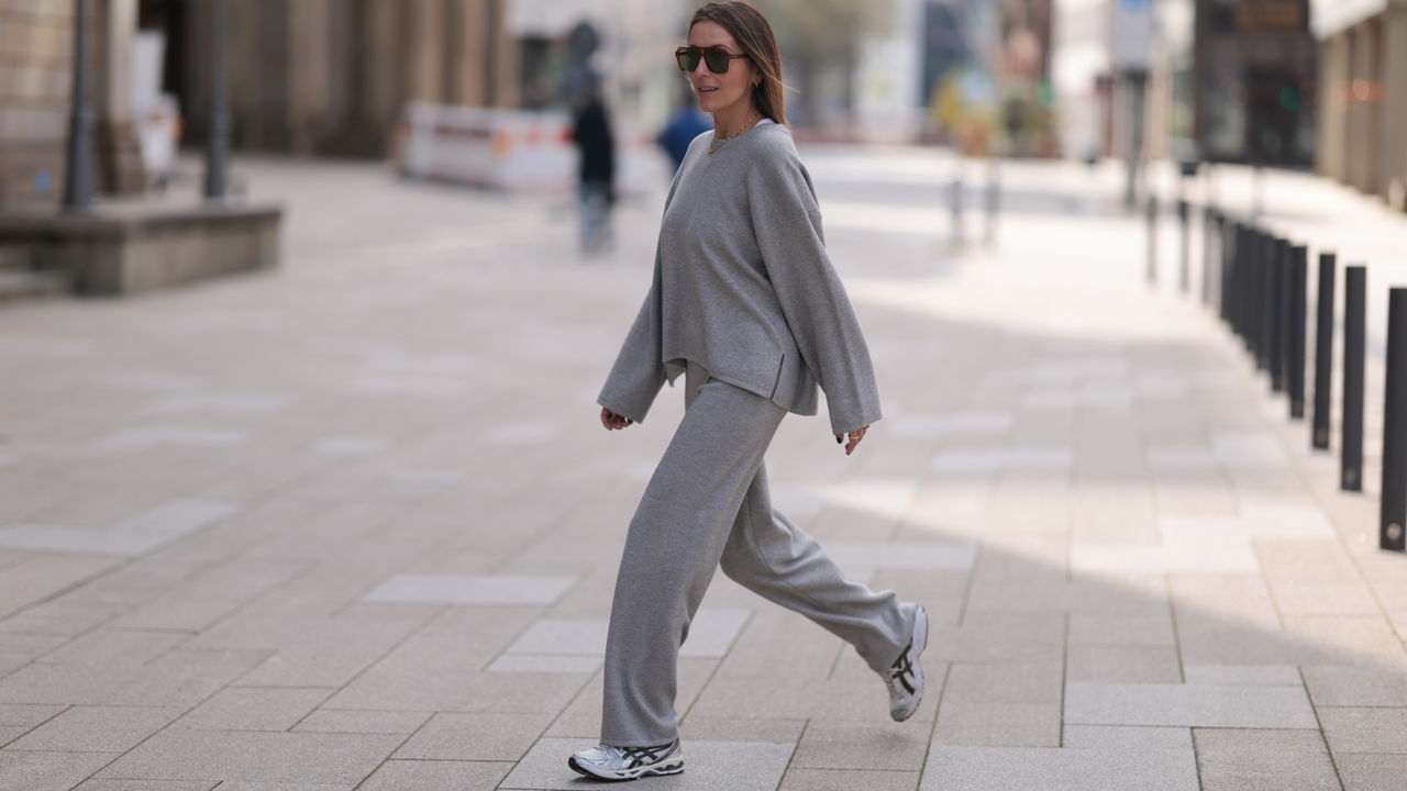 Elise Seitz seen wearing brown vintage aviator sunglasses, gold necklace, Soho Studios light grey wool knit sweater, matching Soho Studios light grey wool knit jogger pants and ASICS white / silver sneakers, on April 20, 2024 in Hamburg, Germany. 