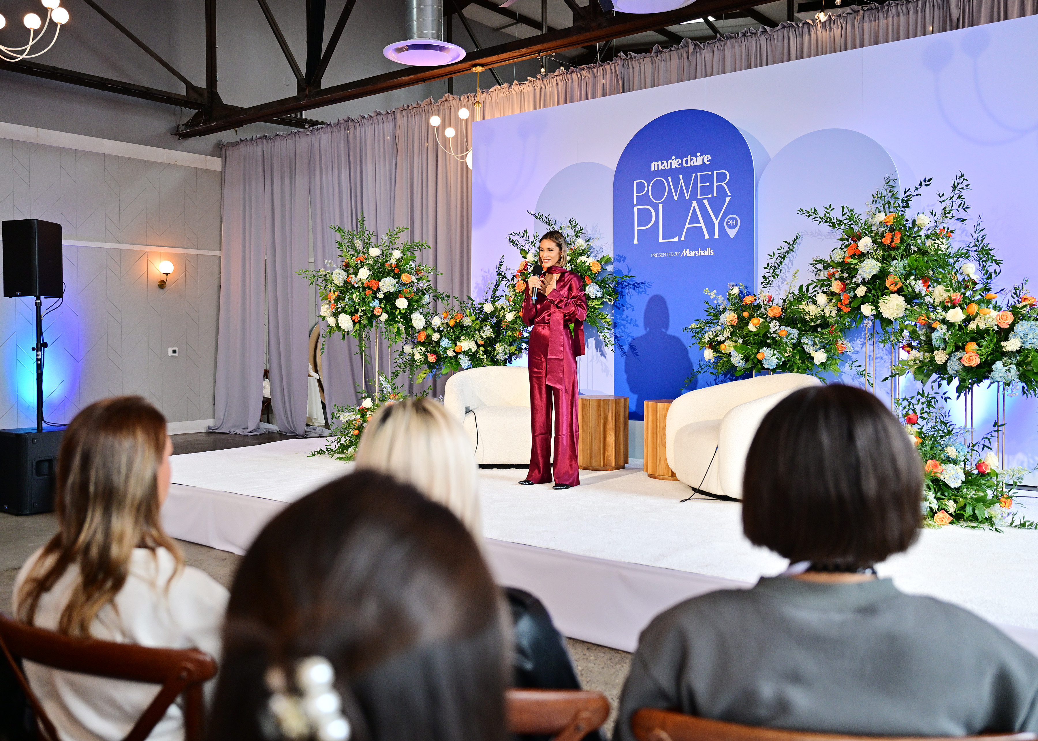 Peloton instructor Aditi Shah leads a meditation exercise during Marie Claire&amp;rsquo;s Power Play summit in Philadelphia, standing on stage in a burgundy satin suit as attendees listen from the audience.