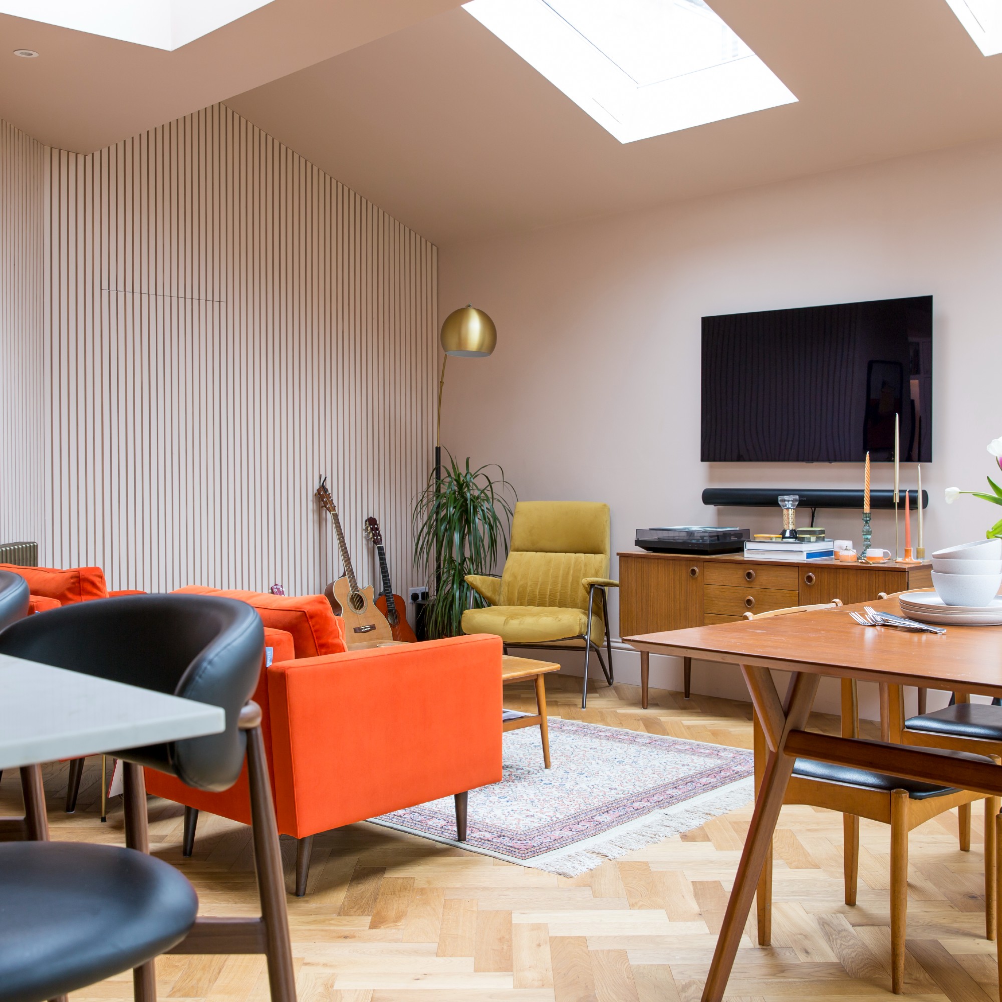 An open-plan living room with a panelled wall and an arched gold-tone floor lamp next to a yellow armchair