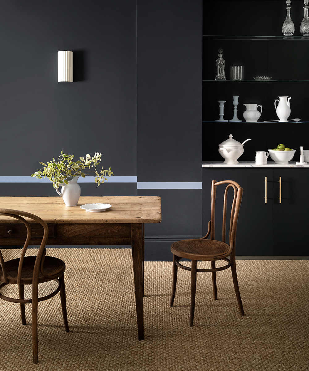 A deep blue kitchen diner with wooden dining table and natural flooring
