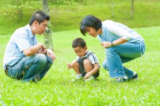 Parents crouch down next to their young son.