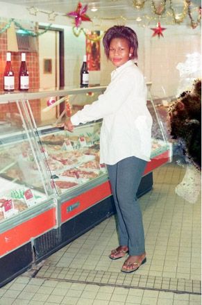 African woman wearing white shirt standing near meat counter