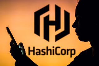 HashiCorp logo on an orange background with the silhouette of a woman holing a smartphone out in front of her face in the foreground