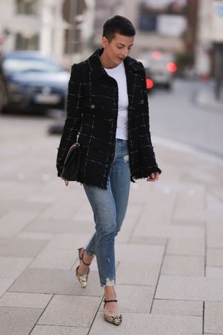 Woman wearing a white tee, boucle jacket and blue skinny jeans