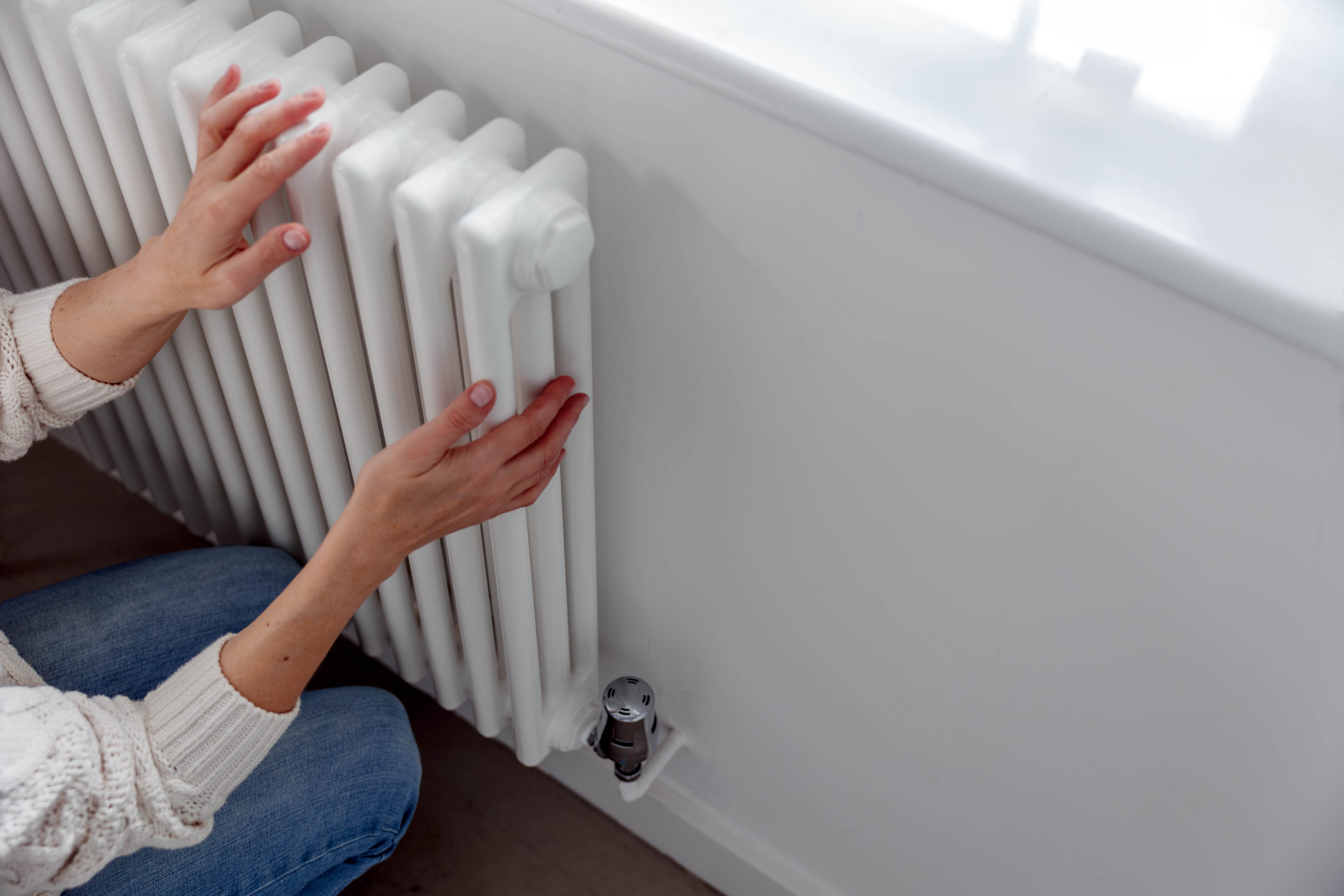 A woman touches the side and front of a radiator.