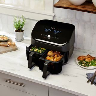 black air fryer in kitchen with chicken and asparagus