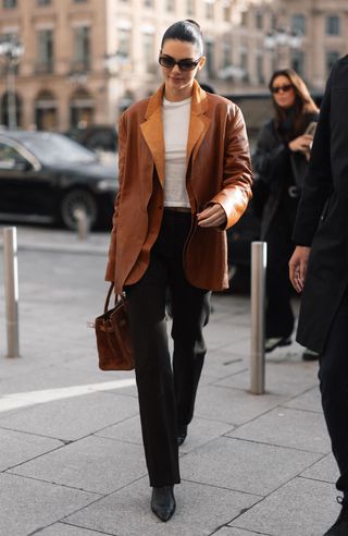 Kendall Jenner in black pants, tan blazer, and white t-shirt.