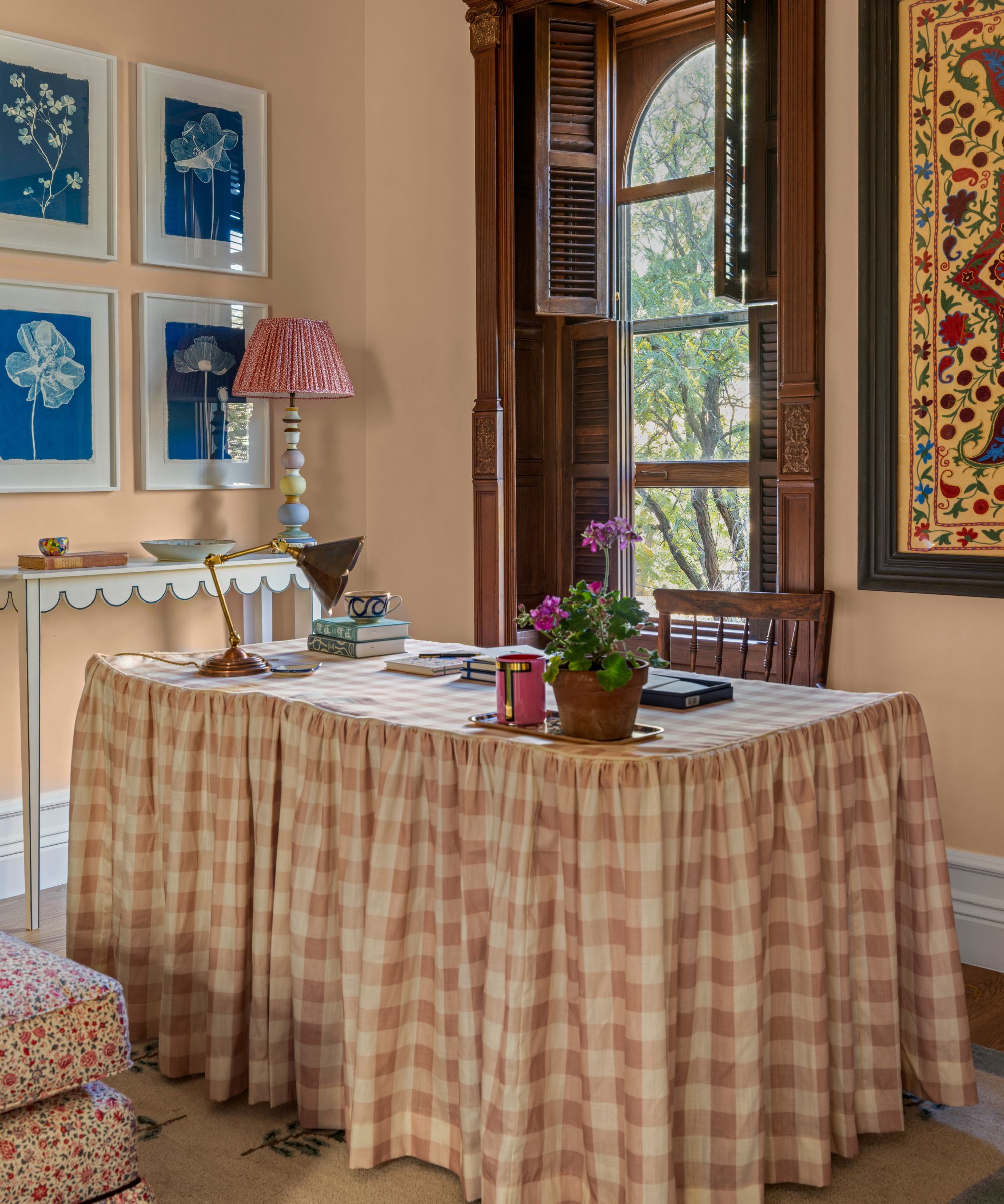 a pale pink home office in a new york brownstone with a pink gingham skirted desk and antique english style decor