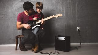 Best guitars for kids: Dad and son play electric guitar