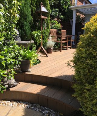 Oak colored composite decking used for outdoor floor surface and stairs with shrub foliage