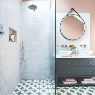 Pink-painted bathroom with a circular mirror and grey cabinet