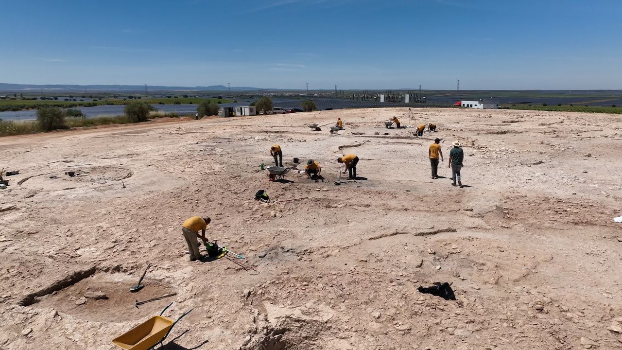 archaeologists work on an excavation in a dusty field