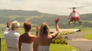 Three members of staff wave towards a red helicopter in Billion Dollar Playground