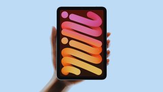 A hand holding up the iPad mini 7 with a colorful background on screen