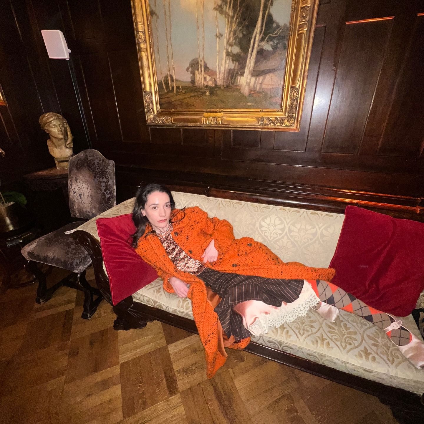 Influencer @oldloserinbrooklyn wears argyle tights with an orange coat and polka dot skirt.
