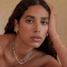 A model wearing earrings, necklaces and bracelets from Astrid & Miyu.