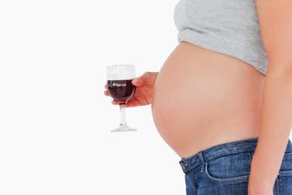 A pregnant woman holds a glass of wine
