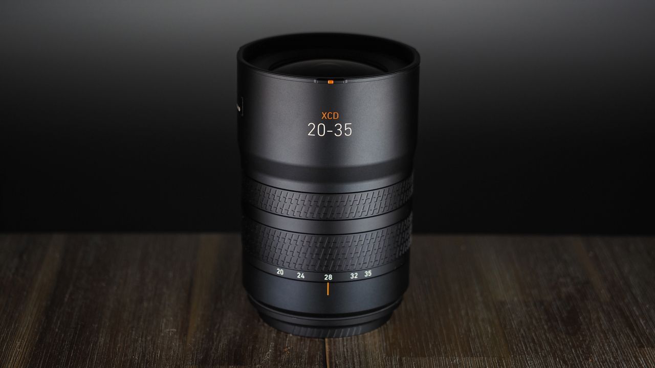 Hasselblad XCD 20-35E lens, moodily lit with subdued lighting, on a wooden surface