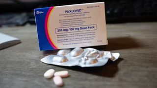 box of the antiviral paxlovid on a table next to a sleeve of the pills