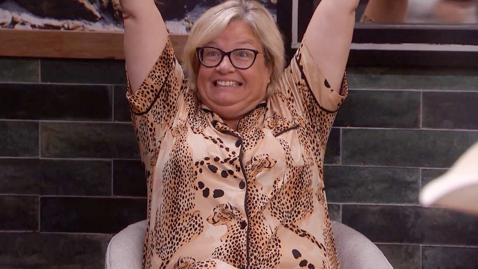 Angela throwing her hands up and celebrating. 