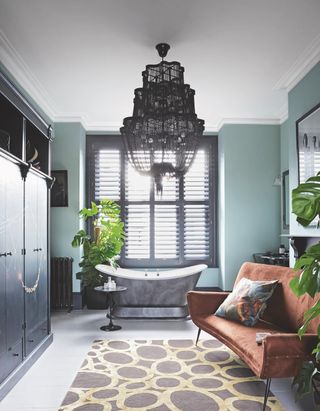 Maximalist blue and gray bathroom with an orange suede sofa and two plants