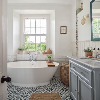 bathroom in period home with contemporary tub, patterned floor tiles, marble topped vanity and jute rug