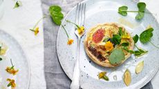 Crab tart on a plate scattered with edible flowers and leaves
