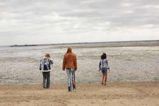 Three girls wearing black and white printed clothing near sea front