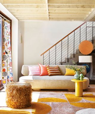 Bright, modern living room with curvaceous cream sofa, yellow side table, colorful rug and cushions