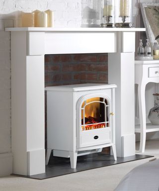 A white electric log burner in a white fireplace surround