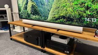 Sonos Arc Ultra soundbar on AV rack underneath TV with nature scene on screen