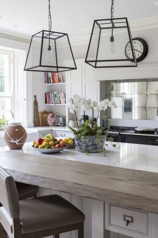 An example of kitchen styles showing a close up shot of an island with leather bar stools below two statement ceiling lights