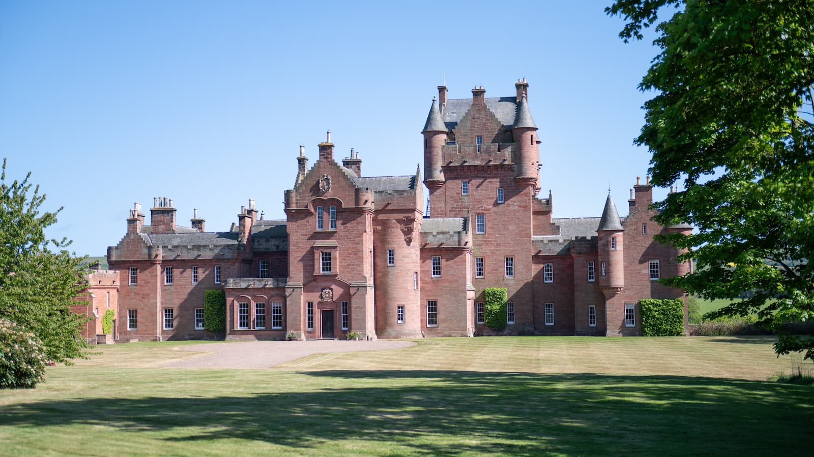 A red sandstone castle with large grounds