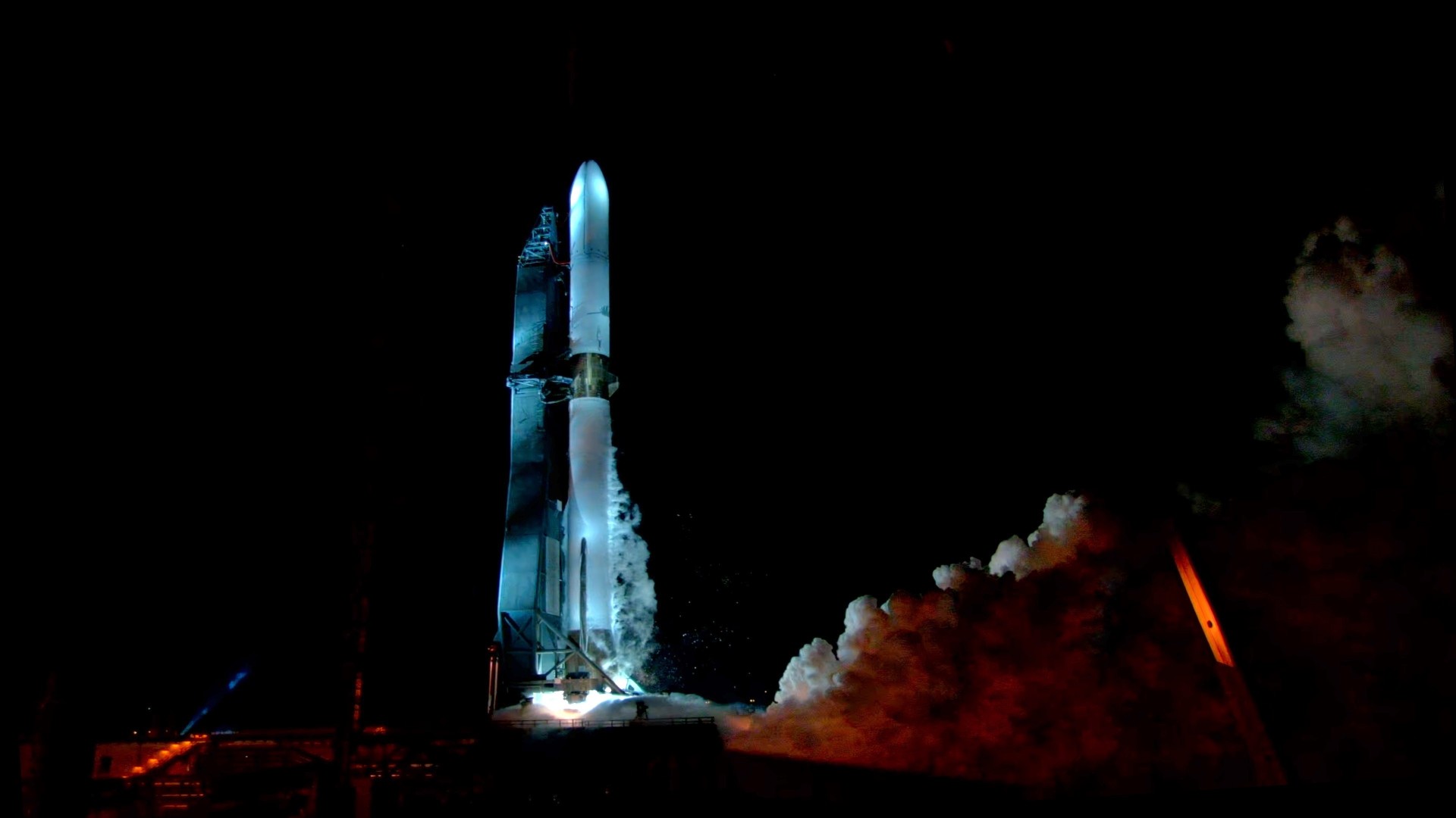 a large white rocket stands upright on a launch pad while a huge cloud of smoke erupts from beneath it