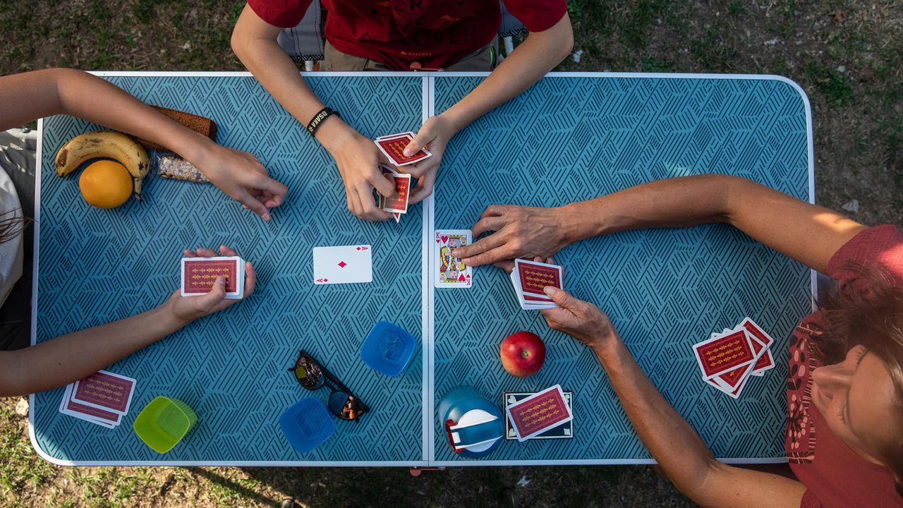 Best camping table: People playing cards on Decathlon Quecha Folding Camping Table