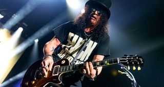 Slash live onstage in London, wearing a top hat, playing a Gibson Les Paul