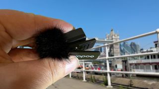 Godox Magic XT1 microphone held in a hand in front of a city scene