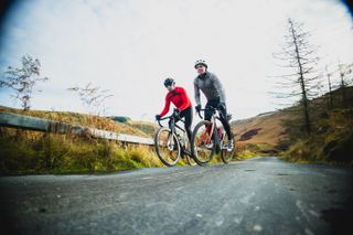 Two cyclists ride on a road in winter kit