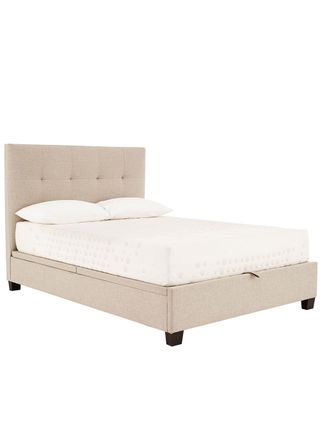 Beige divan bed with uncovered mattress and 2 pillows and button headboard