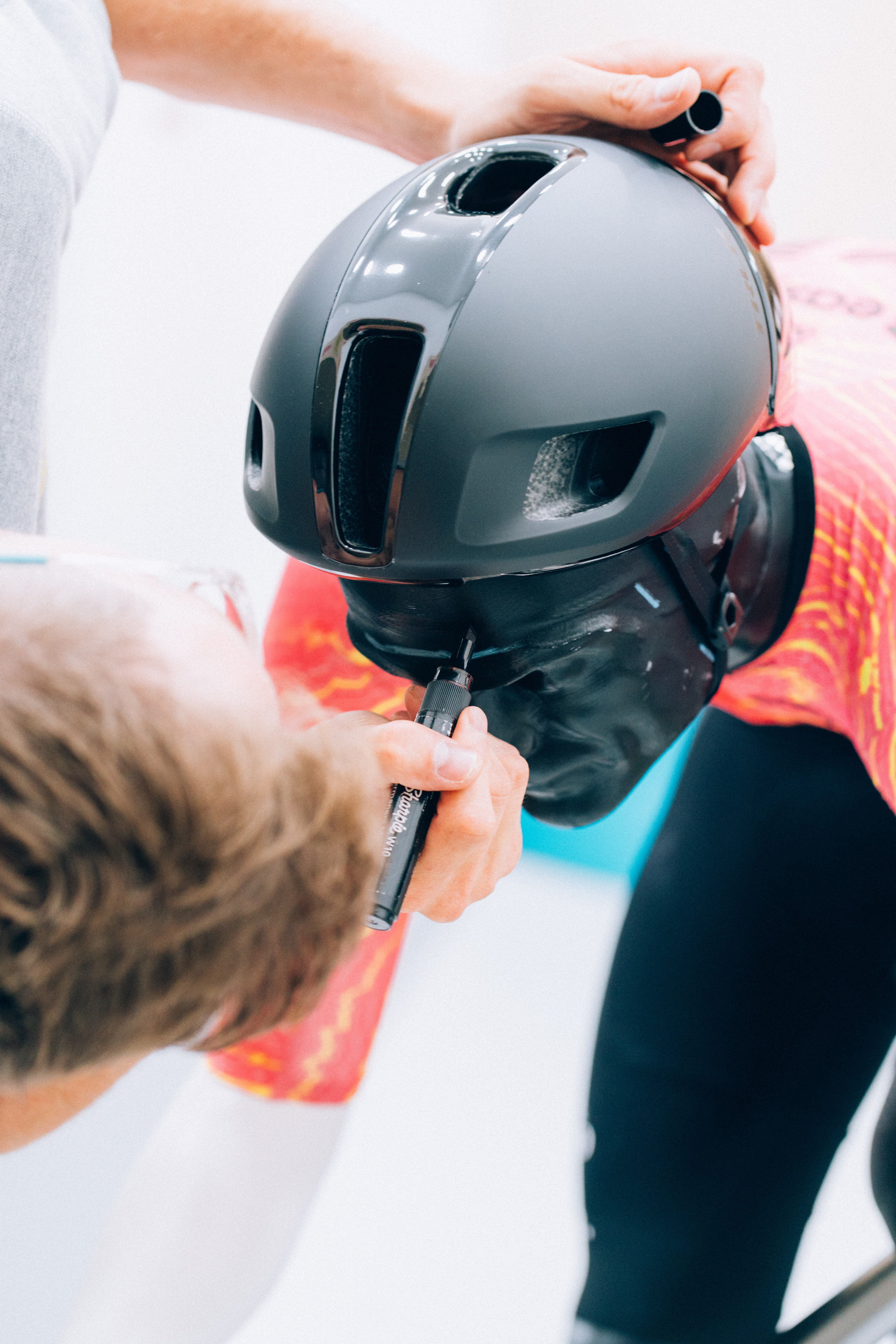 Josh drawing on the mannequin's head to mark the brow point of the helmets