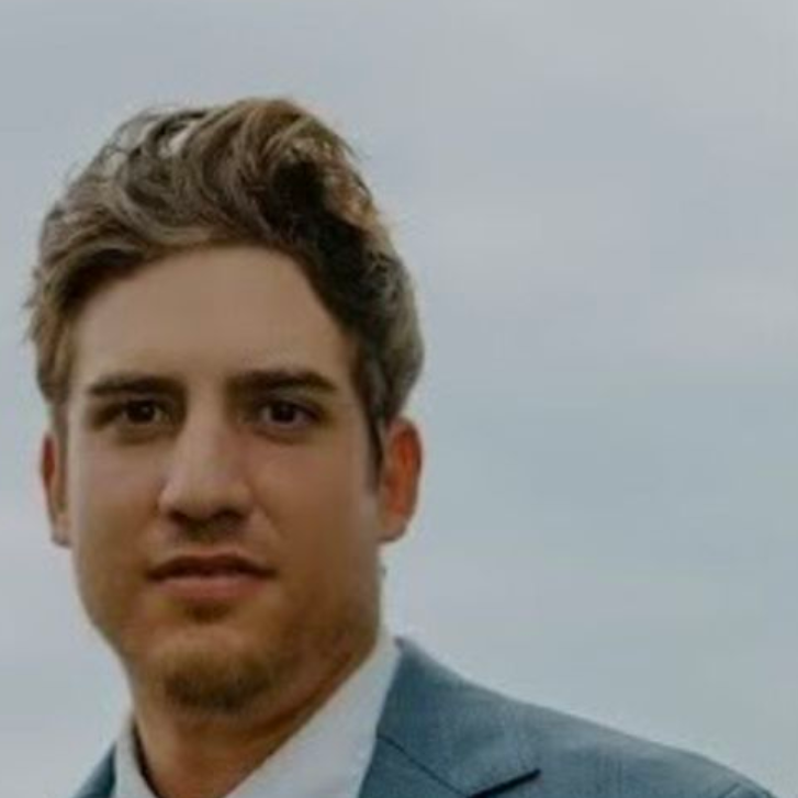 a headshot photo of gardening expert Michael Clark: a man in a gray suit jacket with brown hair looking at the camera