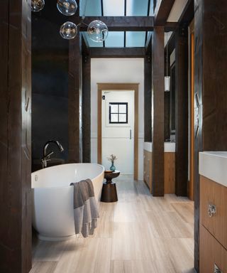 bathroom with freestanding tub, wooden vanities and glass globe pendant