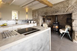 kitchen renovation with exposed stone and lime plaster and concrete kitchen island